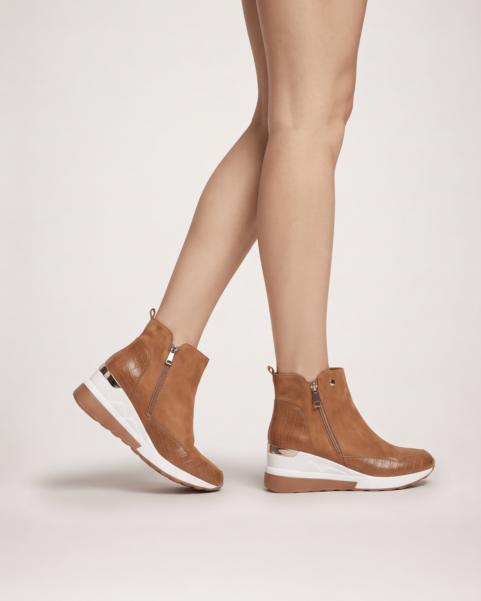 Light brown women’s wedge ankle boots worn in a side-on stepping pose